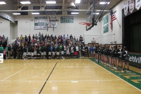 Before the game begins, the student section, basketball team, and cheerleaders honor America during the national anthem. 