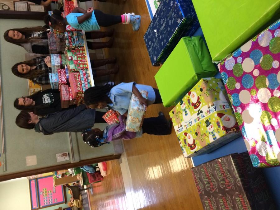 NHS members hand out wrapped shoeboxes filled with gifts at Clay Elementary.