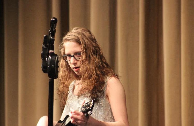 Ella Eder plays a ukulele and sings "Such Great Things" by the Postal Service. 