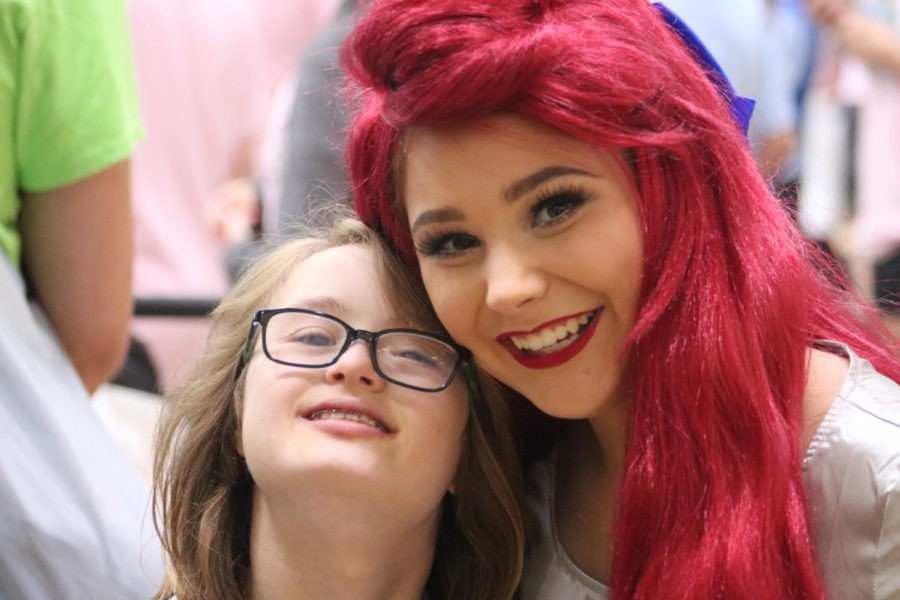 Senior Carly Herman dressed up as Ariel from The Little Mermaid poses for a picture with an athlete.