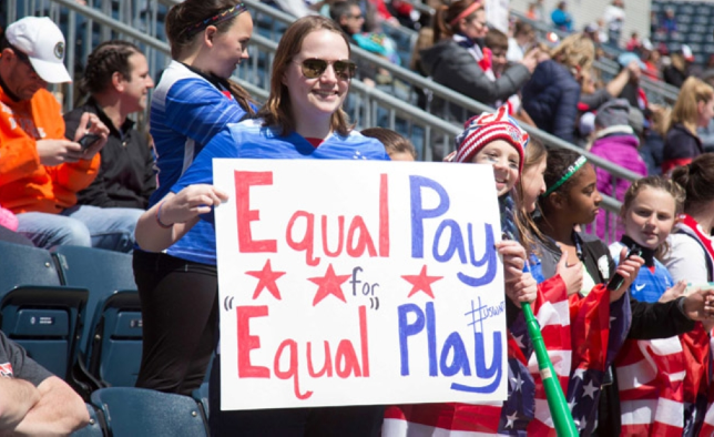 A USA fan holding a sign reading, Equal pay for equal play. Photo Courtesy of Times Oman 