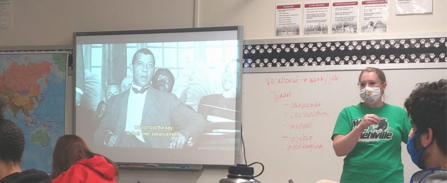 Amy Bush explaining the history of Booker T Washington who is being discussed in a video students are watching.  